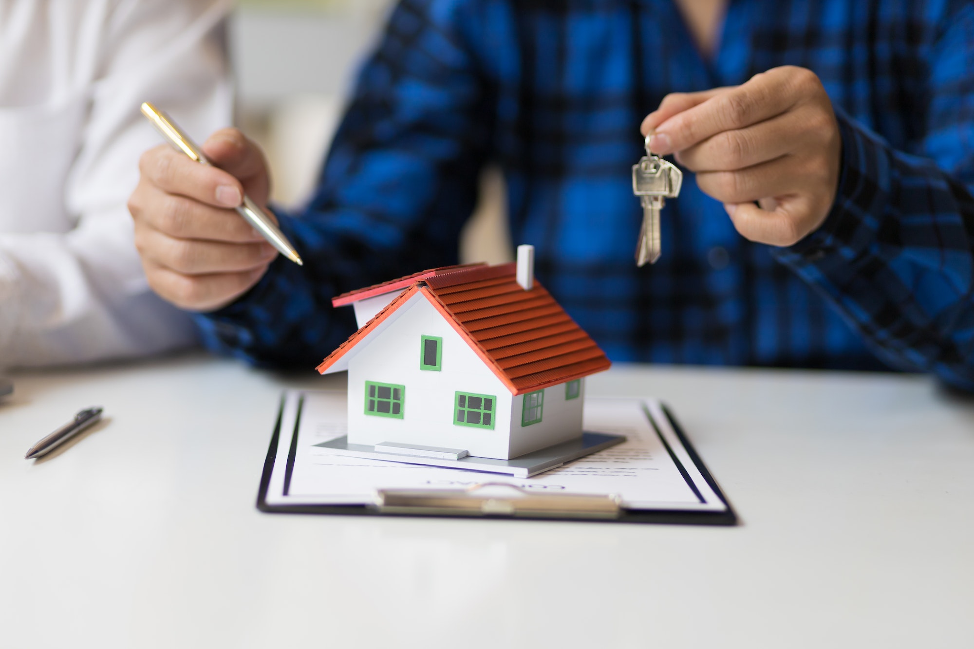 Person holding keys in one hand and a pencil in the other, standing over a small house - Image representing foreclosure and home ownership in Nevada